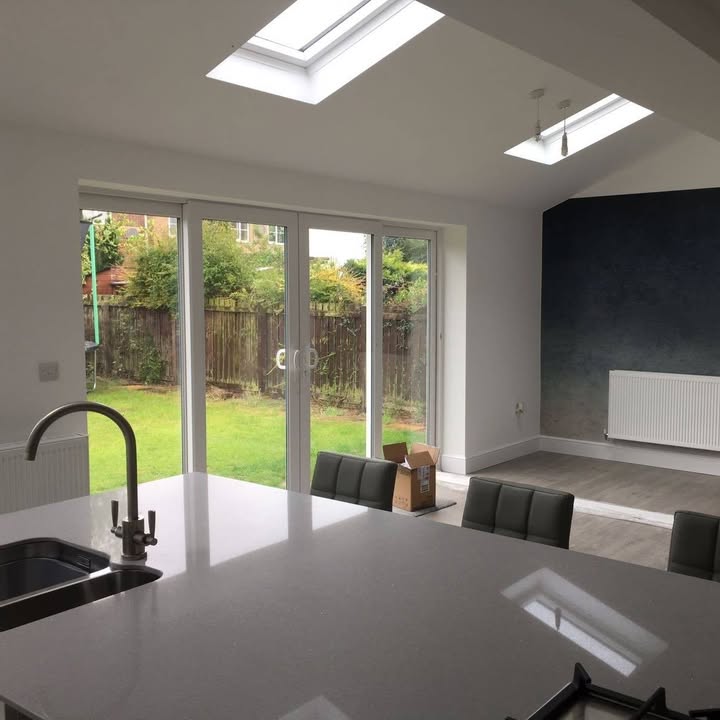 Inside a finished extension: a vaulted ceiling with roof windows, sliding doors to the garden and a kitchen island