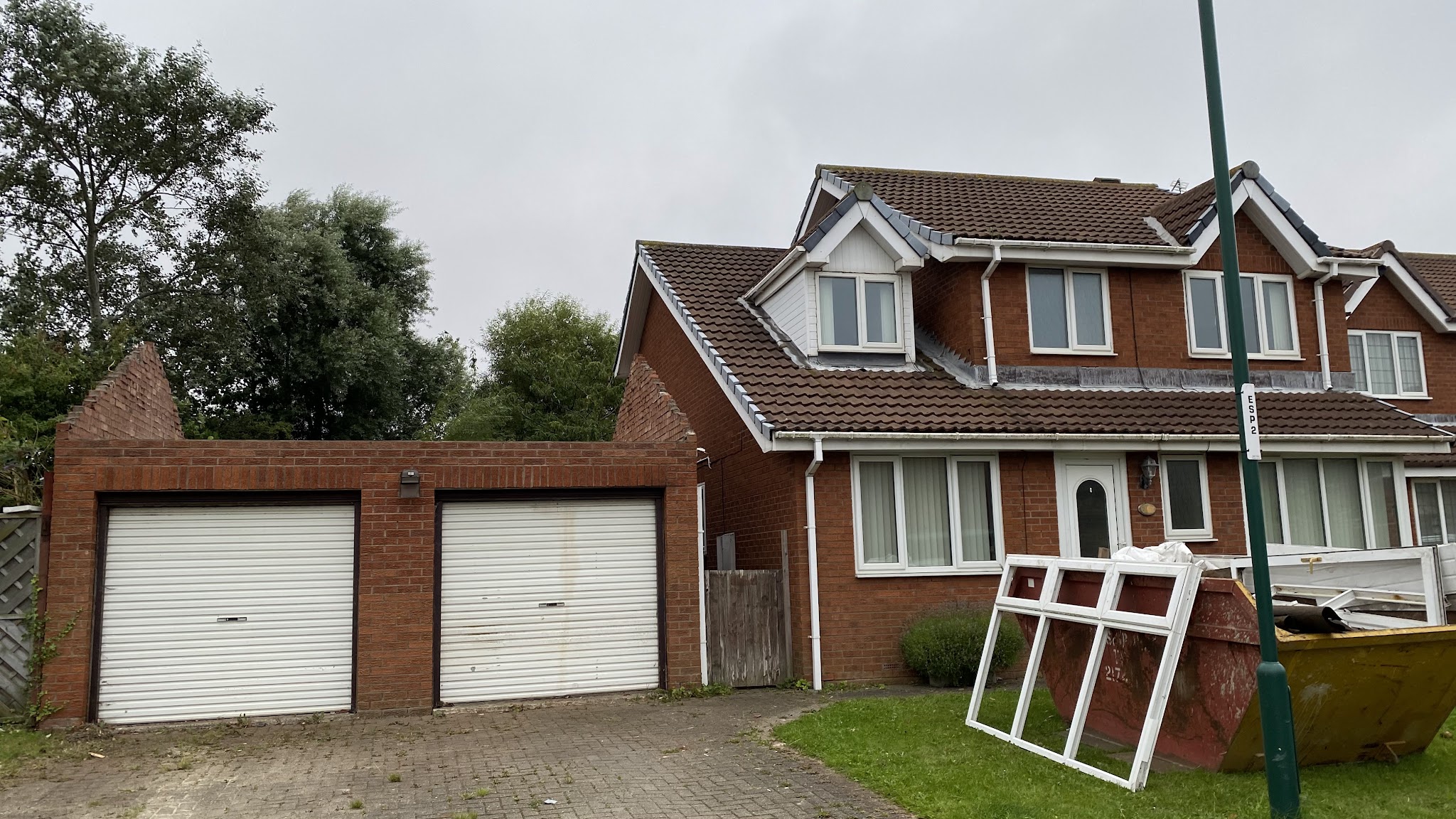 A red-brick detached house with a separate double garage beside it, before work started