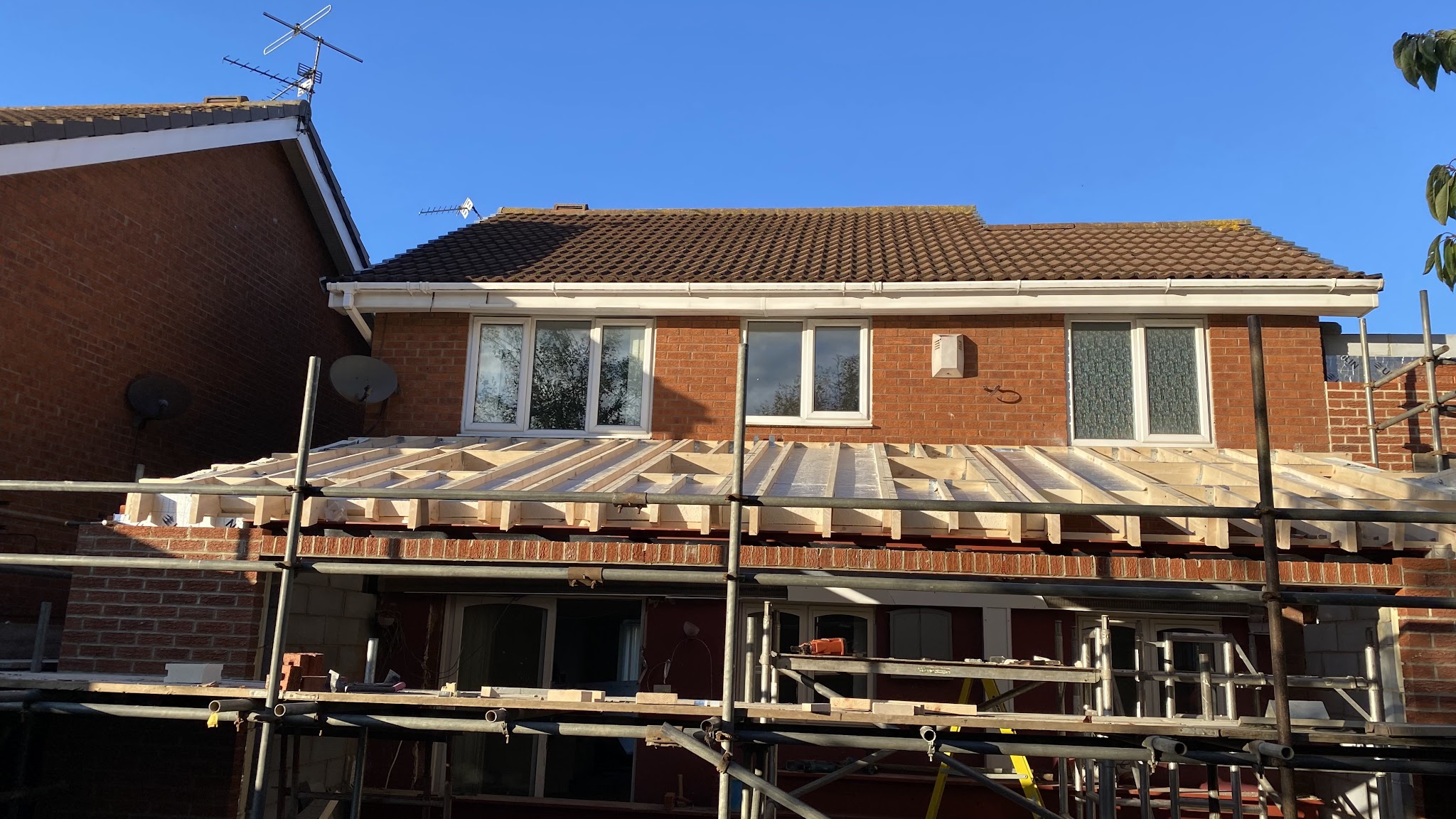 The new rear extension under scaffolding with timber roof joists going on
