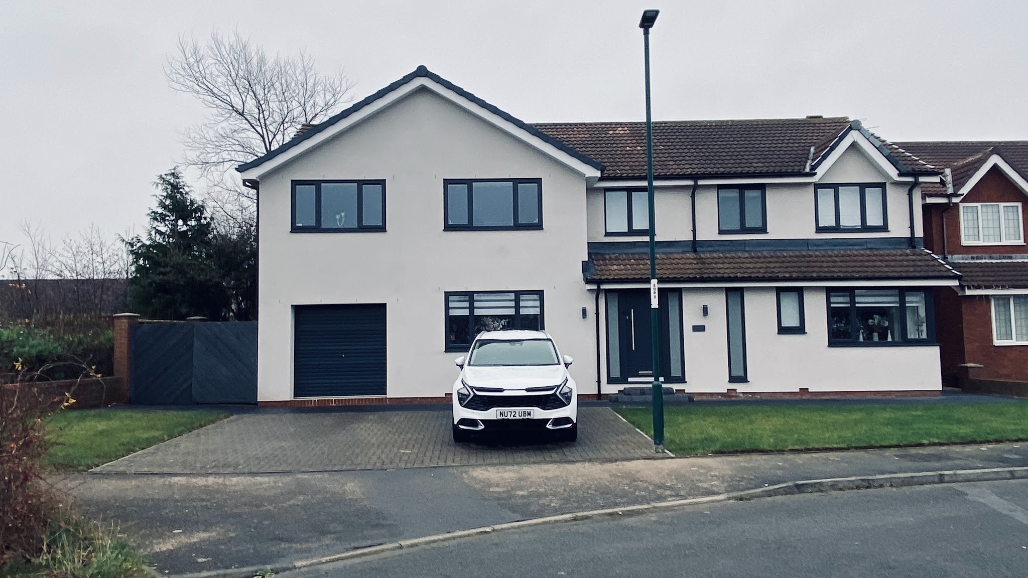 The finished house fully rendered in off-white with anthracite windows, garage door and front door